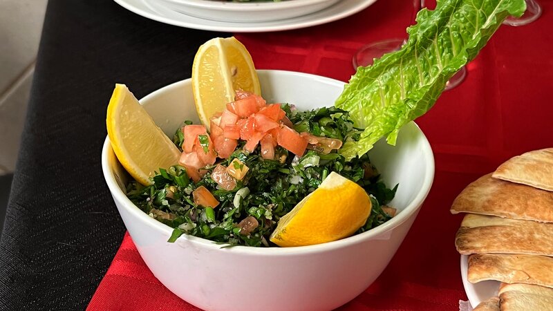 Tabbouleh salad topped with tomatoes and lemon wedges